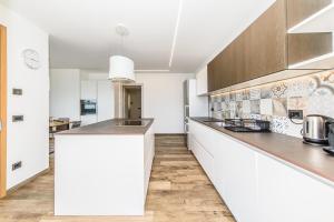 a kitchen with white counters and wooden cabinets at Alpine Aura Loft- Privacy, Relax, Mountain View in Saint-Christophe