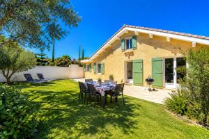 a house with a table and chairs in the yard at Villa Papillons Narbonne 'Jardin & Clim' 'Proche Centre & Plages' in Narbonne