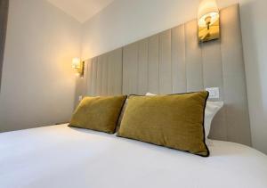 a bedroom with a white bed with two yellow pillows at Hôtel Derby Eiffel in Paris +17 photos
