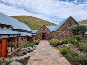 a stone building with a pathway in front of a mountain at Tenahead Lodge & Spa in Rhodes