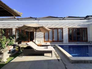 a house with a swimming pool and an umbrella at Amy Guesthouse Nusa Dua in Nusa Dua