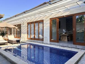 a swimming pool in front of a house at Amy Guesthouse Nusa Dua in Nusa Dua