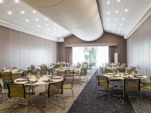 a dining room with tables and chairs and a ceiling at Novotel Lyon Bron in Bron