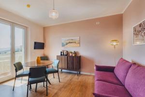 a living room with a purple couch and a table at My Tuscany Pink Suite in San Quirico dʼOrcia +9 photos