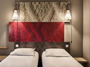 two beds in a room with a red wall at ibis Moulins in Moulins +53 photos