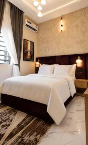 una camera da letto con un grande letto con lenzuola bianche di TOMA Hotel a Uyo