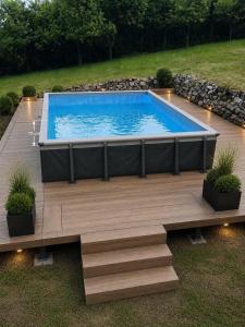 a swimming pool in a yard with a wooden deck at Nyugalmas Vendégház in Lénárddaróc