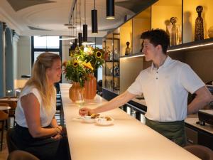 a man and a woman standing at a counter in a restaurant at Hotel Maison Maastricht Centrum - Handwritten Collection in Maastricht