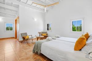 a white bedroom with a large bed and two chairs at Finca Biniatzau by 3VILLAS in Alaior