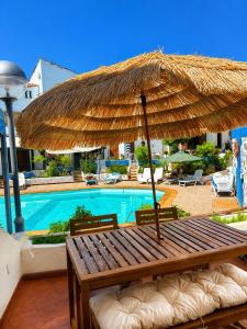 a wooden bench with an umbrella next to a swimming pool at El Molino Agaete in Puerto de las Nieves