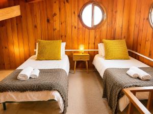 two beds in a room with wooden walls and a window at El Molino Agaete in Puerto de las Nieves