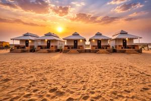 a row of huts on the beach at sunset at Royal Salma Resort A family Luxury Camp 