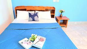 a bed with a blue blanket and books on it at The cabana guesthouse in Cha Am
