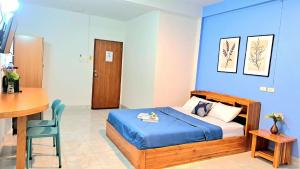 a bedroom with a bed and a table and a desk at The cabana guesthouse in Cha Am