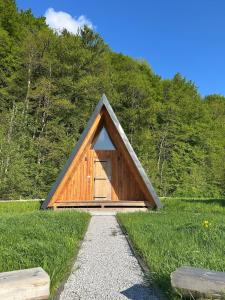 a small wooden barn with a triangular roof in a field at Glamping cabins in Gorenja Vas