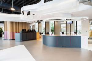 an office lobby with a reception desk and a white ceiling at YOTEL Amsterdam in Amsterdam