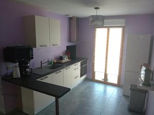a kitchen with purple walls and a sink and a window at Le Cottage d'Aubigny in Aubigny-sur-Nère +6 photos
