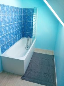 a bathroom with a tub and a blue tiled wall at Le Cottage d'Aubigny in Aubigny-sur-Nère