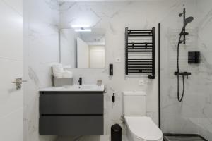 a bathroom with a toilet and a sink and a mirror at Torrejón Suites 2 in Torrejón de Ardoz