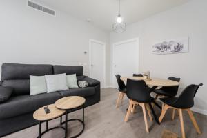 a living room with a black couch and tables at Torrejón Suites 2 in Torrejón de Ardoz