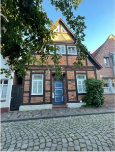 a brick house with a blue door on a cobblestone street at Rooms for rent Nienburg Weser in Nienburg