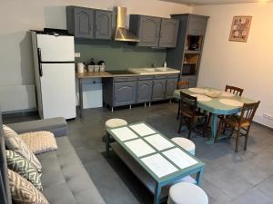 a kitchen with a couch and a table and a refrigerator at Maison « La grange » climatisée in Azay-le-Rideau