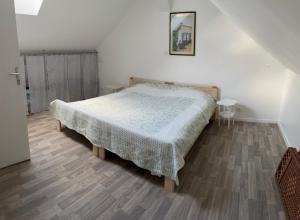 a bedroom with a bed and a wooden floor at Maison « La grange » climatisée in Azay-le-Rideau