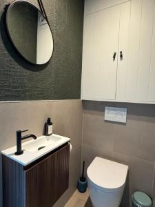 a bathroom with a sink and a toilet and a mirror at Sand & Sea - Adults Only in Middelkerke +19 photos