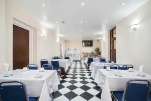 a restaurant with white tables and chairs and a checkered floor at Cranbrook Hotel in Ilford