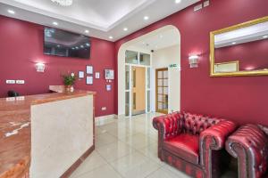 a red lobby with a red couch and a mirror at Cranbrook Hotel in Ilford