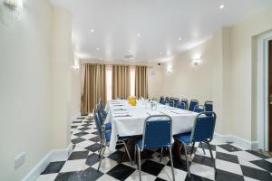 a meeting room with a long table and blue chairs at Cranbrook Hotel in Ilford
