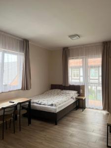 a bedroom with a bed and tables and windows at Pokoje Blisko Morza SUNSET in Ustka