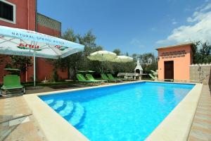 a swimming pool with chairs and umbrellas next to a building at Sobe ROOMS TEA in Buje