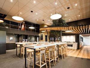 a restaurant with white tables and chairs in a room at ibis Poitiers Site du Futuroscope in Chasseneuil-du-Poitou