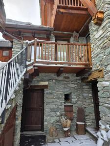 a wooden deck on the side of a stone building with a door at la casa del marmottaio in Crépin +4 photos