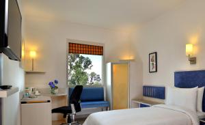a hotel room with a bed and a desk and a window at Red Fox Hotel Bhiwadi in Bhiwadi