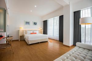 a hotel room with a bed and a couch at HARRIS Hotel & Conventions Malang in Malang +8 photos