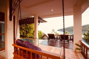 a porch of a house with a swing at Salad Buri Resort- SHA Extra Plus in Salad Beach