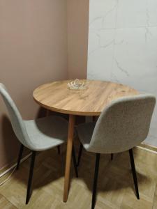 a wooden table with two chairs and a bowl on it at Apartman Petrov in Pančevo