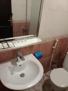 a bathroom with a white sink and a toilet at Qimmat AlAwali Hotel in Az Zahrāʼ