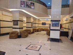 a lobby with chairs and a tv in a building at Qimmat AlAwali Hotel in Az Zahrāʼ
