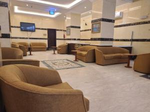 a waiting room with couches and a flat screen tv at Qimmat AlAwali Hotel in Az Zahrāʼ +7 photos