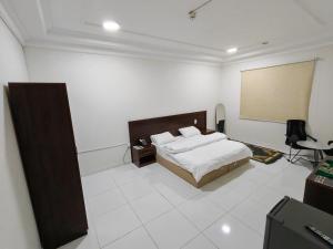a bedroom with a bed and a desk and a screen at فندق فاديه الذهبي in ‘Ushayrah