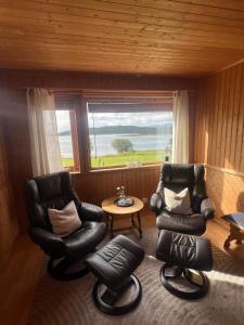 a living room with two chairs and a table and a window at Senja seaside retreat in Senja +28 photos