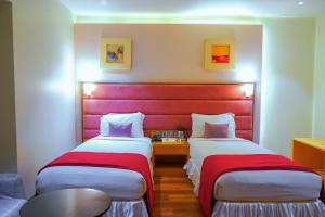 two beds in a room with a red headboard at Middleton Inn in Kolkata