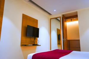 a bedroom with a bed and a flat screen tv at Middleton Inn in Kolkata