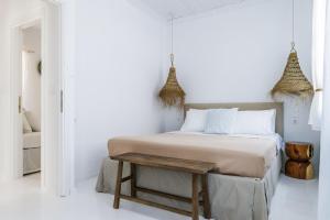 a white bedroom with a bed and a wooden table at Maison Mariel in Skopelos Town +28 photos