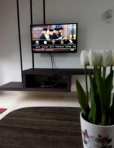 a vase with white flowers in front of a tv at 4H Guesthouse Cameron Highland in Brinchang