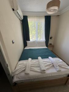 a bed in a room with a window and towels at Minikbiotel in Erdek