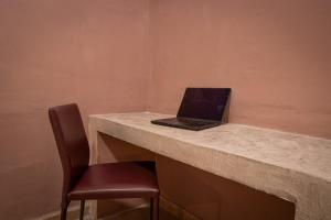 a laptop computer sitting on a counter with a chair at Capital O Adhoc Barrio Antiguo in Monterrey
